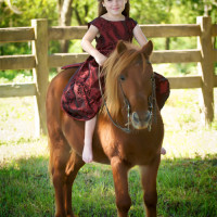 A portrait of a girl riding a pony barefoot.