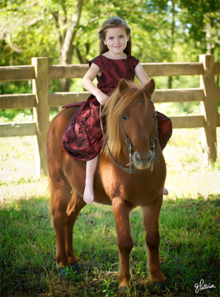 A portrait of a girl riding a pony barefoot.